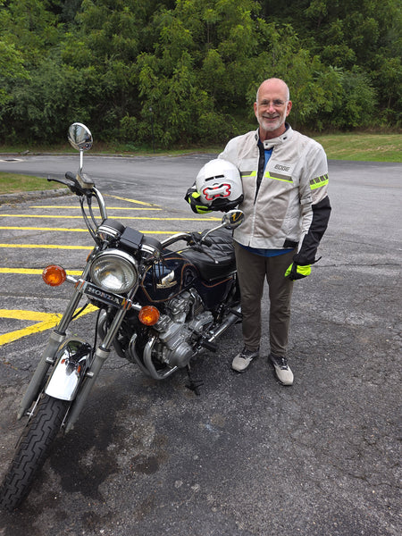 Barry holding his helmet with a Brake Free attached next to his 1980's Honda